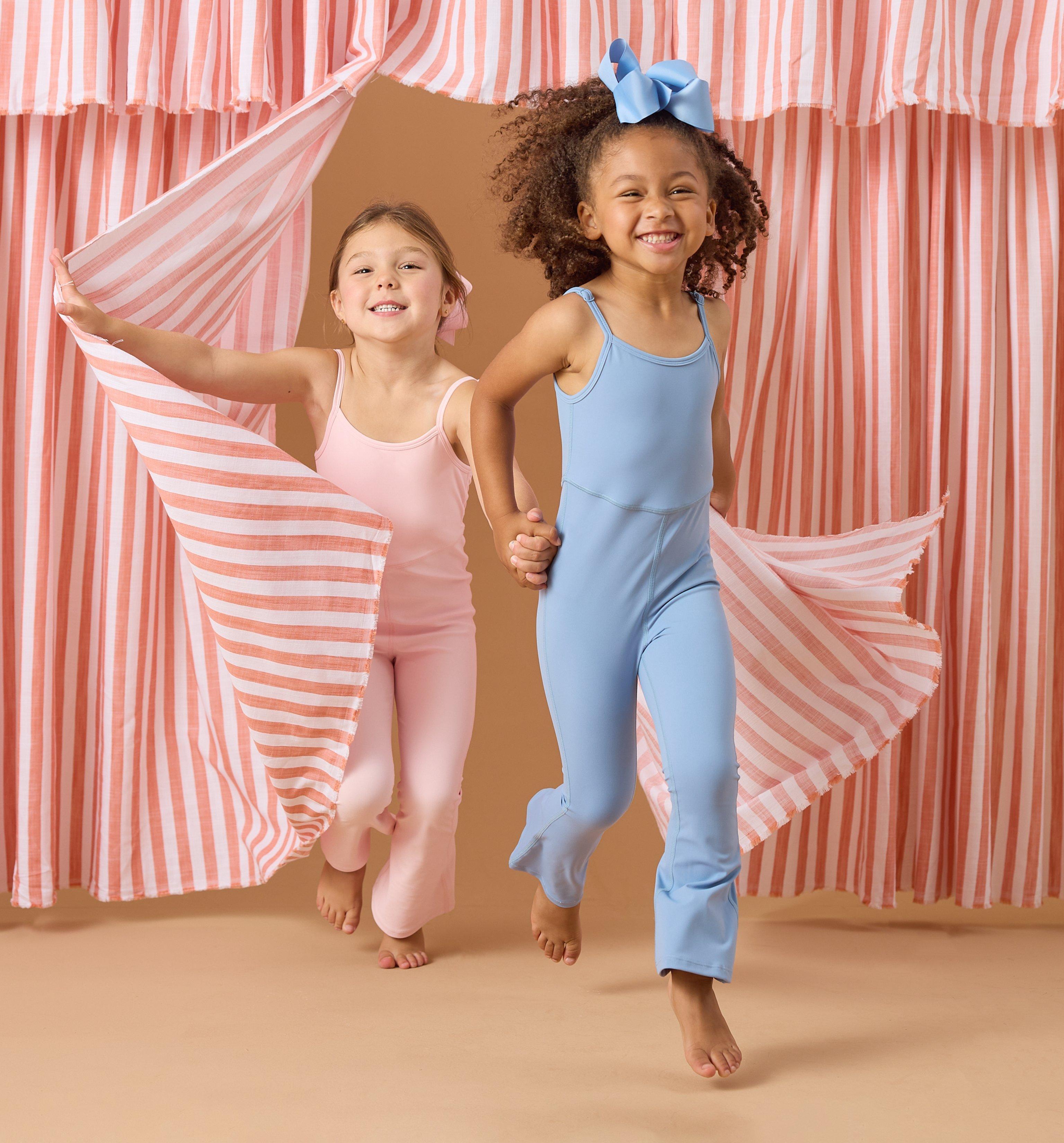 Two girls wearing blue and pink athletic jumpsuits.