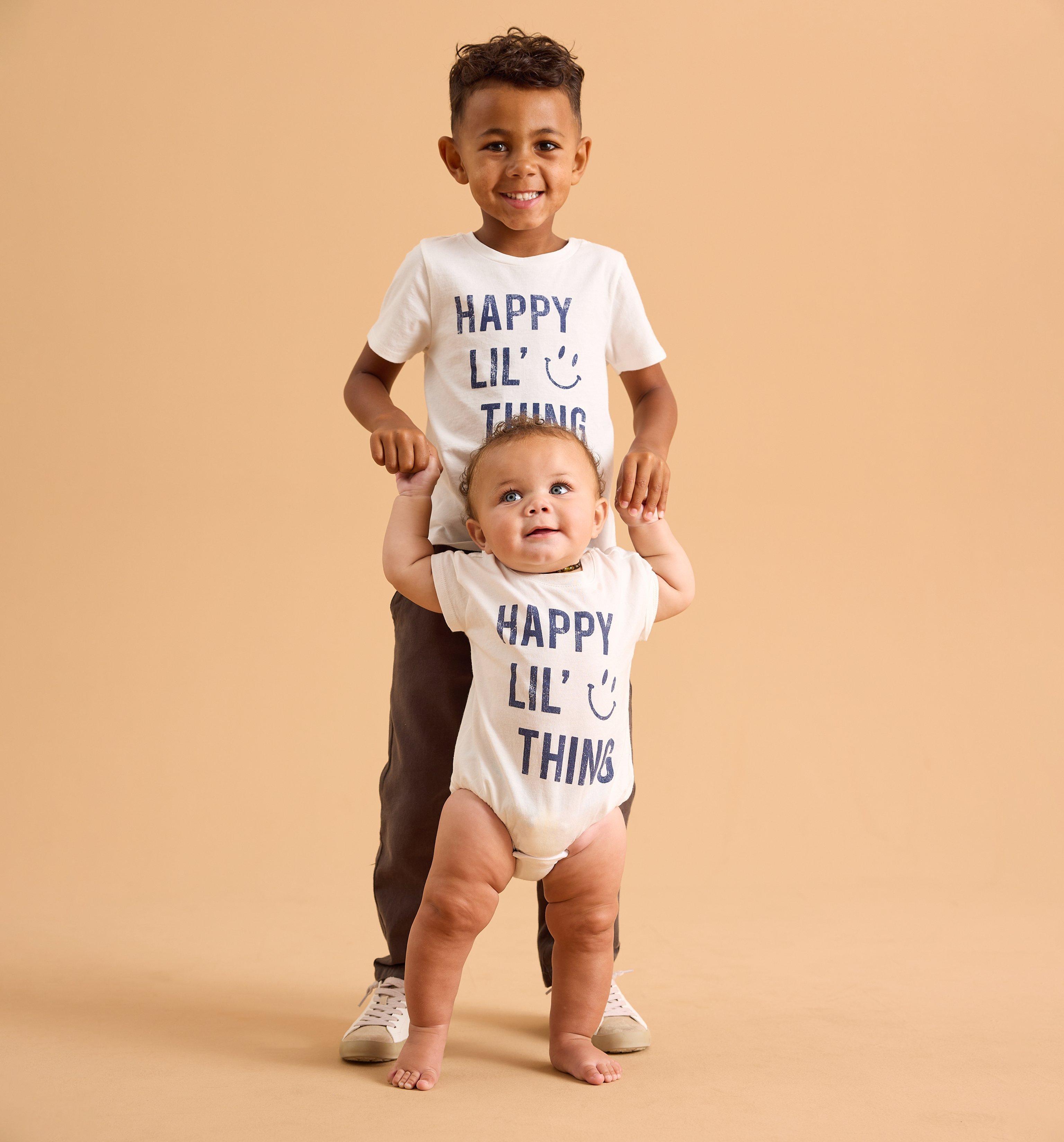 Young boy and baby wearing matching white and blue graphic tshirts.