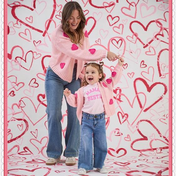 Mom and daughter wearing matching pink heart cardigans.