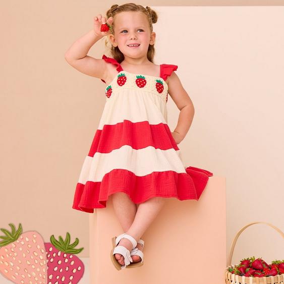 Little girl wearing a red and white dress with strawberries on it.