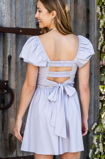 Woman wearing a lavender mini dress with an open back and a bow