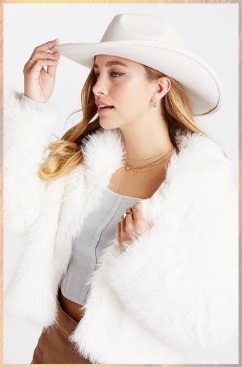 Woman wearing a corset top, white fur jacket, and white suede cowboy hat