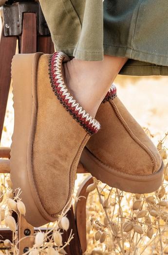 Tan cloud slippers with red and white knitting around the rim.