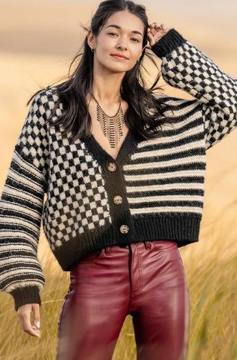 Woman wearing a black and white checkered cardigan with maroon leather pants.