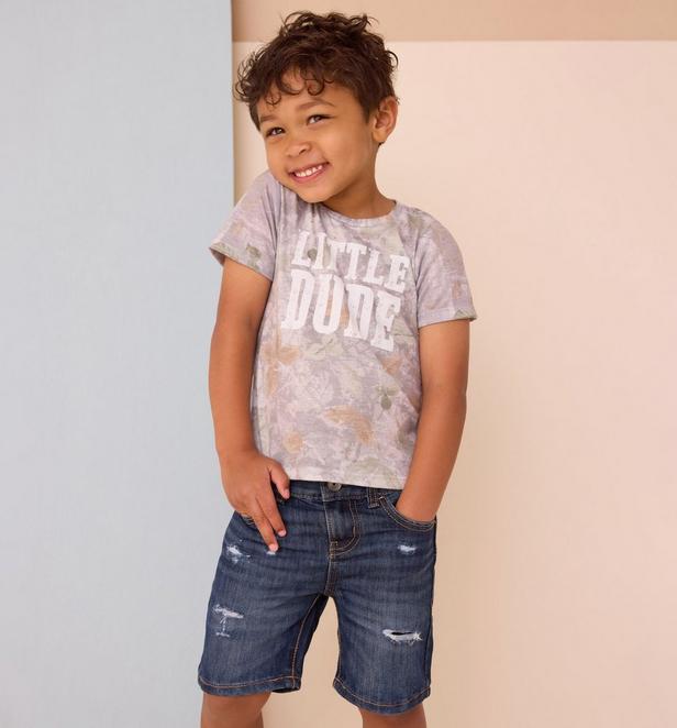 Little boy wearing a camo shirt and jean shorts.