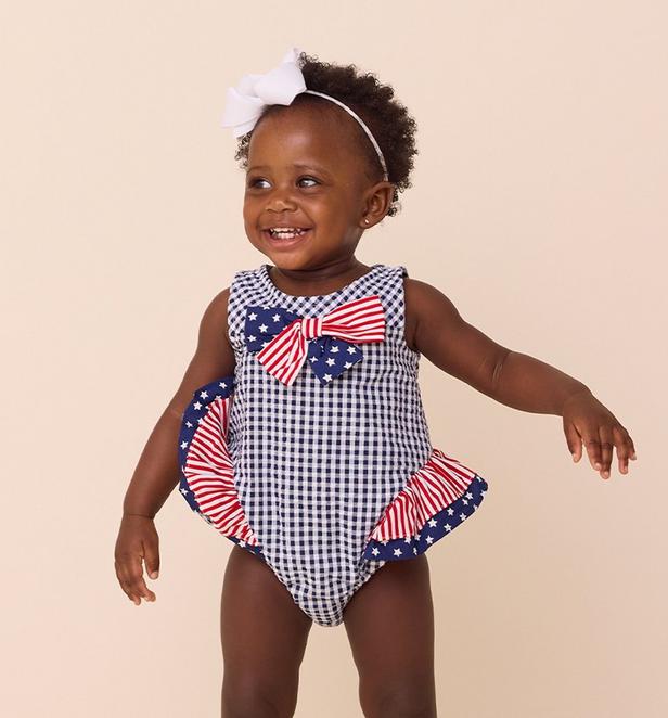 Little girl wearing a red white and blue one piece.