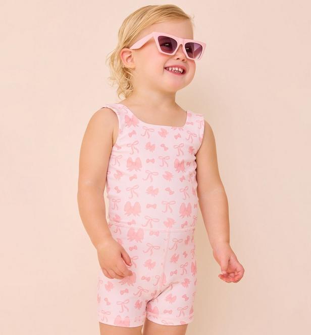 Little girl wearing pink bow unitard.