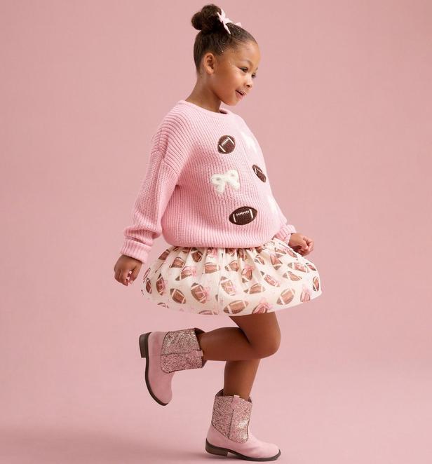 Little girl wearing a game day themed sweater and skirt with football patterns