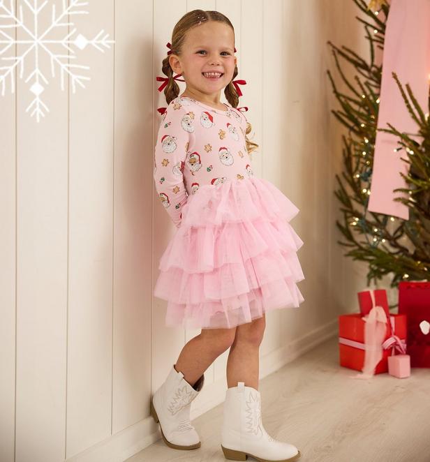 Little girl wearing pink dress with santa faces on it.