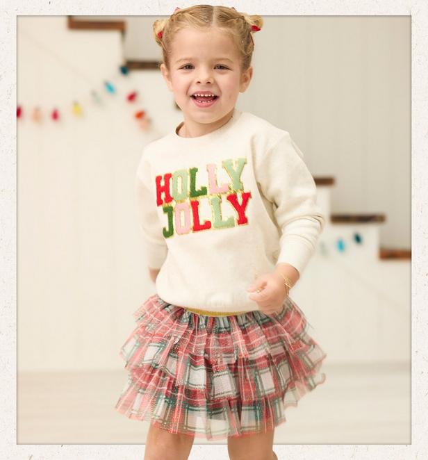 Little girl wearing a Holly Jolly long sleeve pullover and plaid skirt