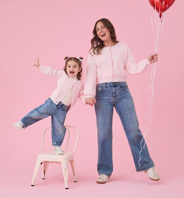 Girl and Mom wearing matching pink cardigan with white bows.