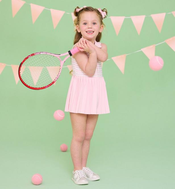 Girl wearing pink tennis set holding a racket.