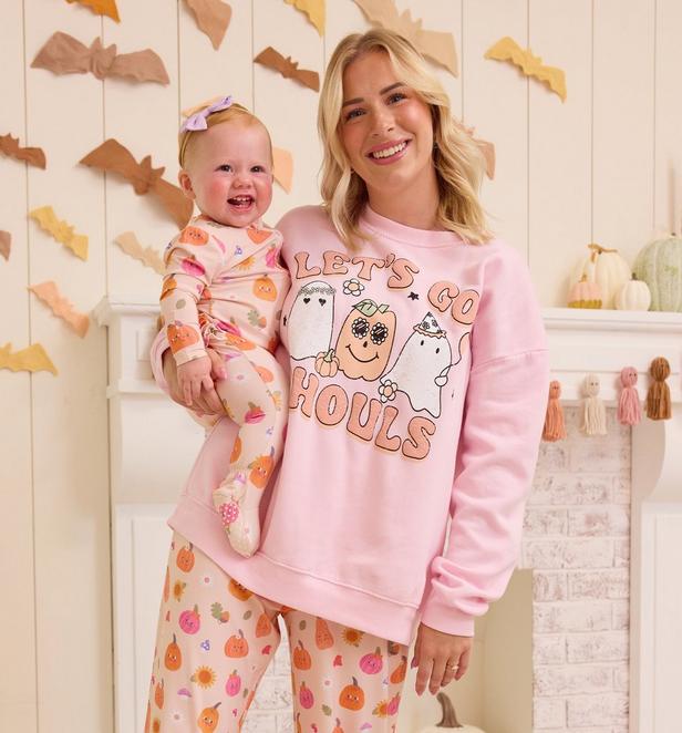 Mama and little girl wearing matching pink and orange halloween themed pajamas