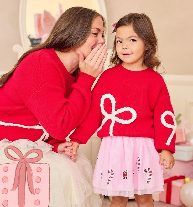 Mama and little girl wearing matching red sweaters with white bow detail