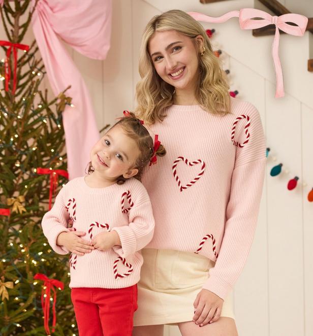 Woman and young girl wearing matching pink candy cane sweaters