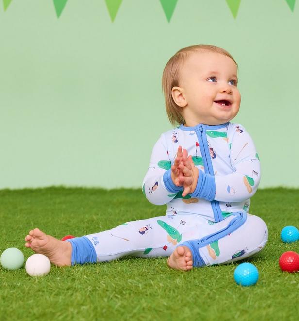 Little boy wearing blue PJ onesie with golf icons on it.