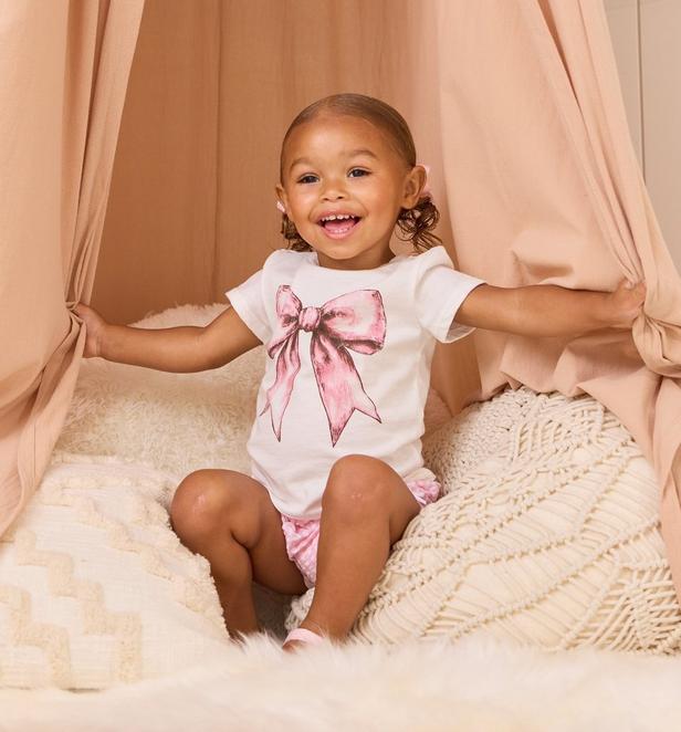 Little girl wearing pink bow graphic shirt.