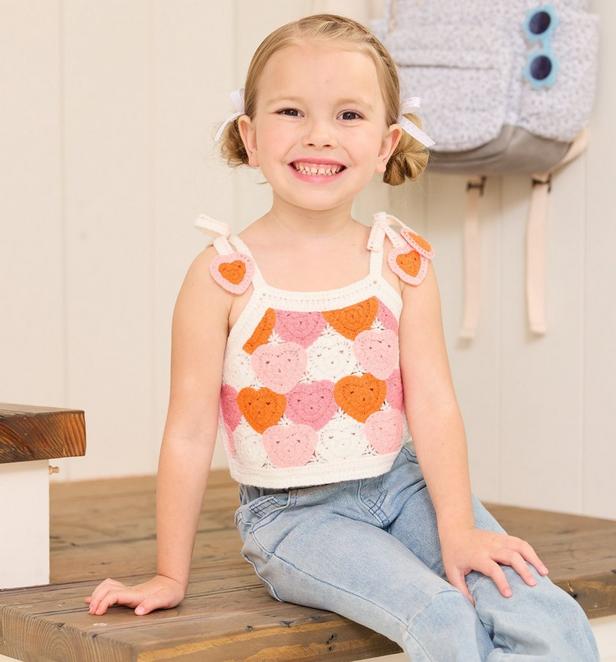 Little girl wearing crochet heart top.