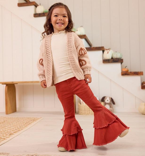 Little girl wearing red flare bottoms and light pink pumpkin cardigan