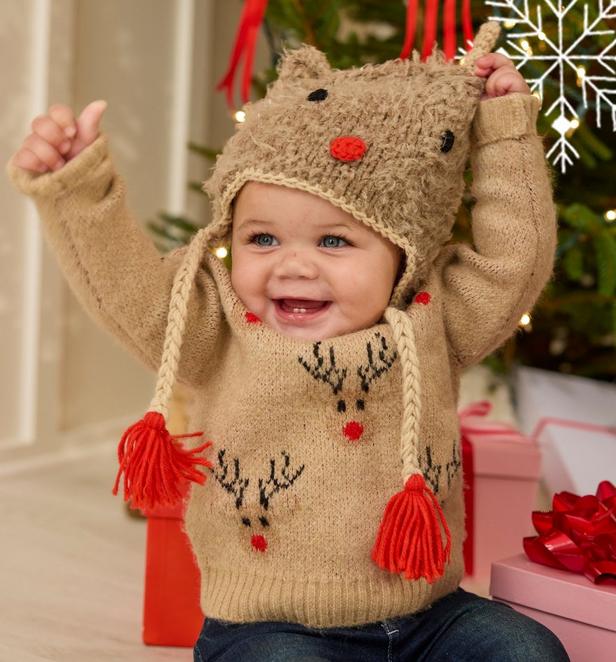 Little boy wearing tan and red reindeer beanie, and matching sweater.