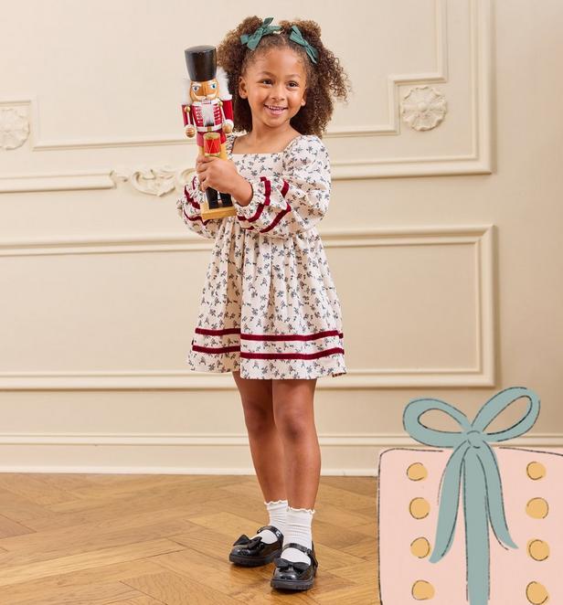 little girl wearing a white floral dress with burgundy detailing