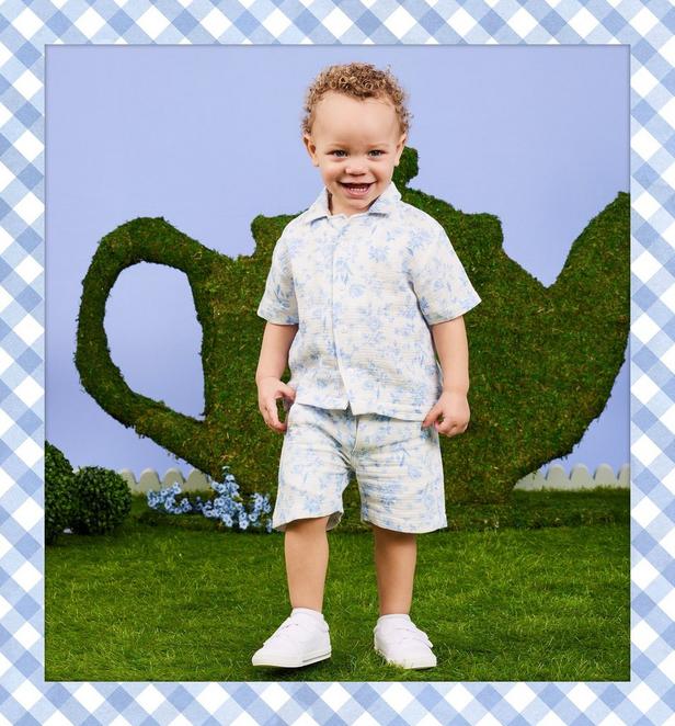 Young boy wearing matching blue and white floral shirt and pants.