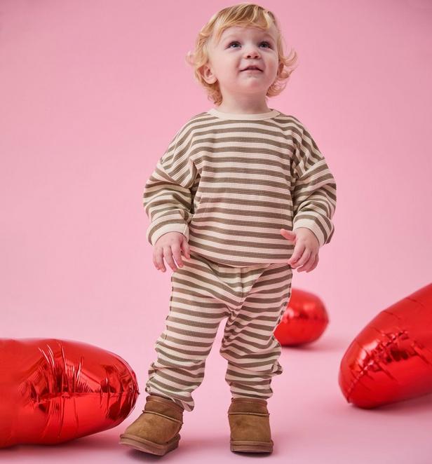 Little boy wearing a matching brown and white stripped lounge set.