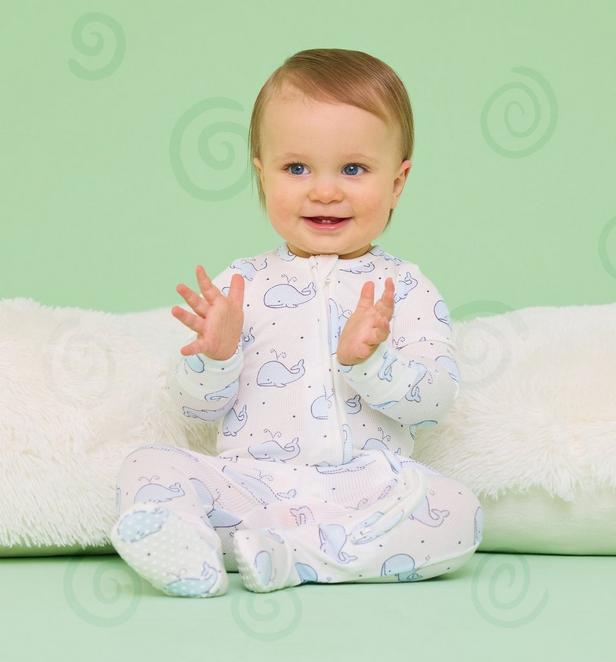 Little boy wearing a blue whale white onesie.