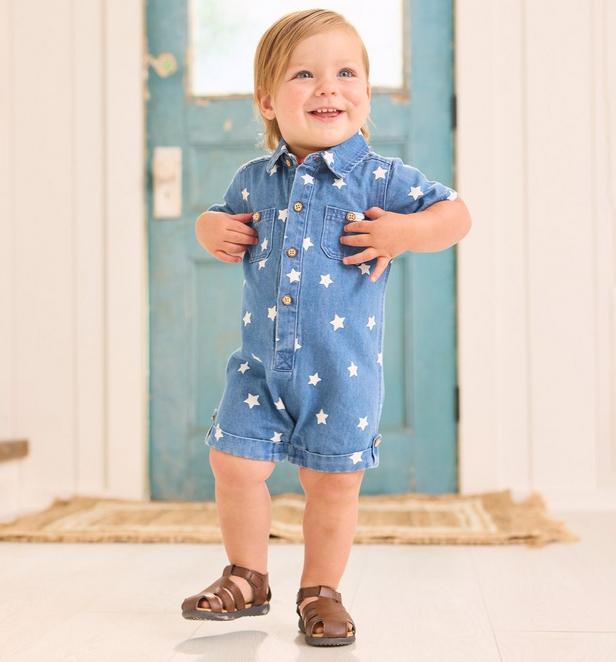 Little boy wearing a denim one piece with stars on it.