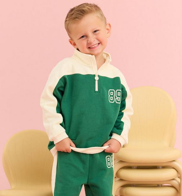 Little boy wearing a green and cream game day themed pullover quarter zip