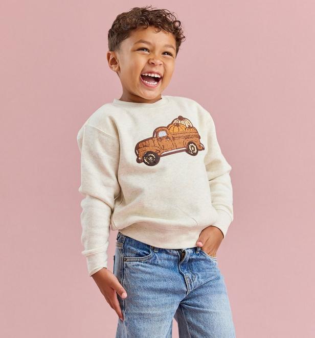 little boy wearing a cream colored pullover with a vintage truck and pumpkins graphic