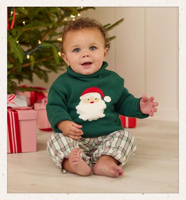 Little boy wearing a dark green Santa sweater with plaid pants