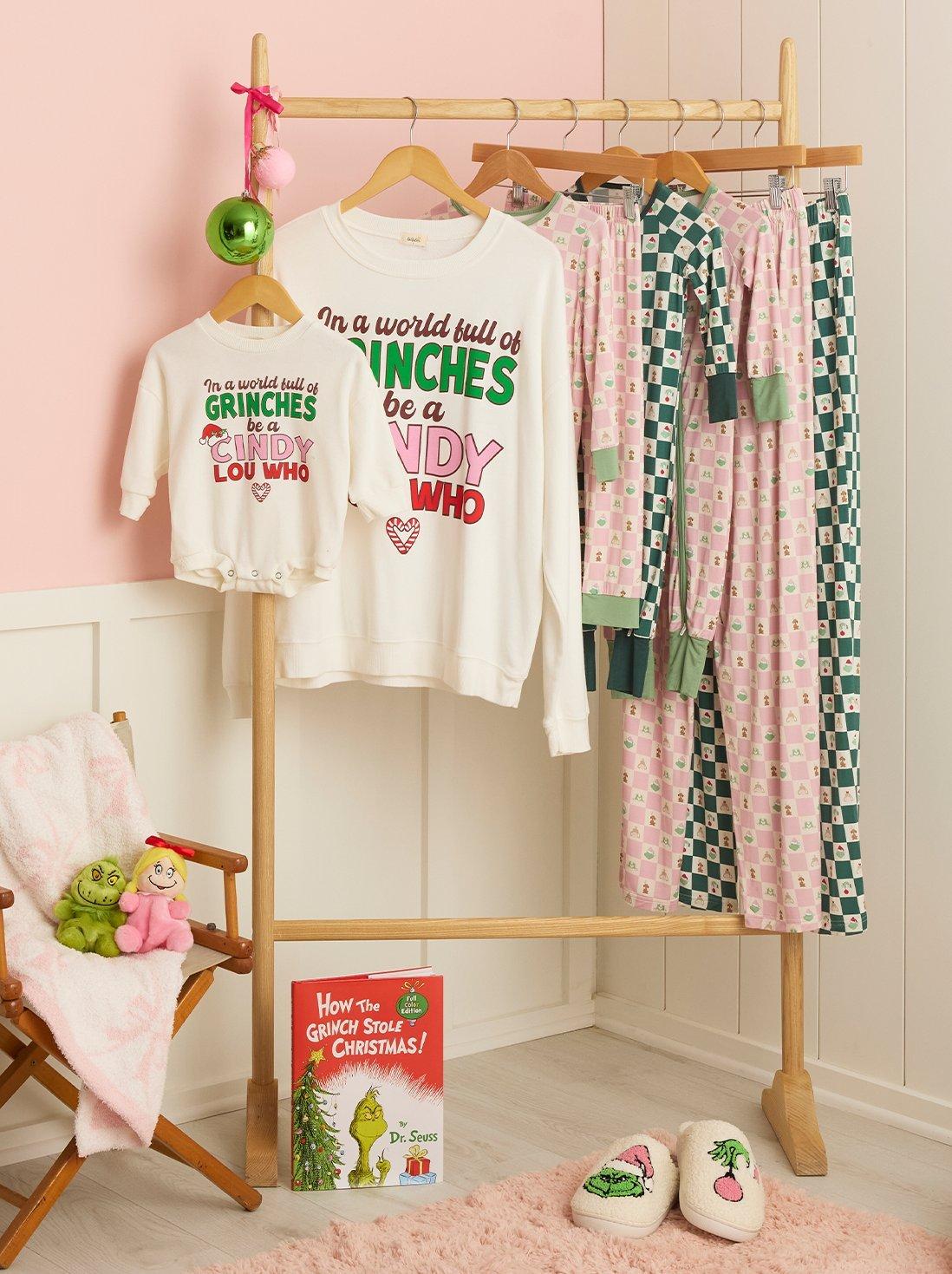 Matching red, green, and pink grinch apparel on a hanging rack