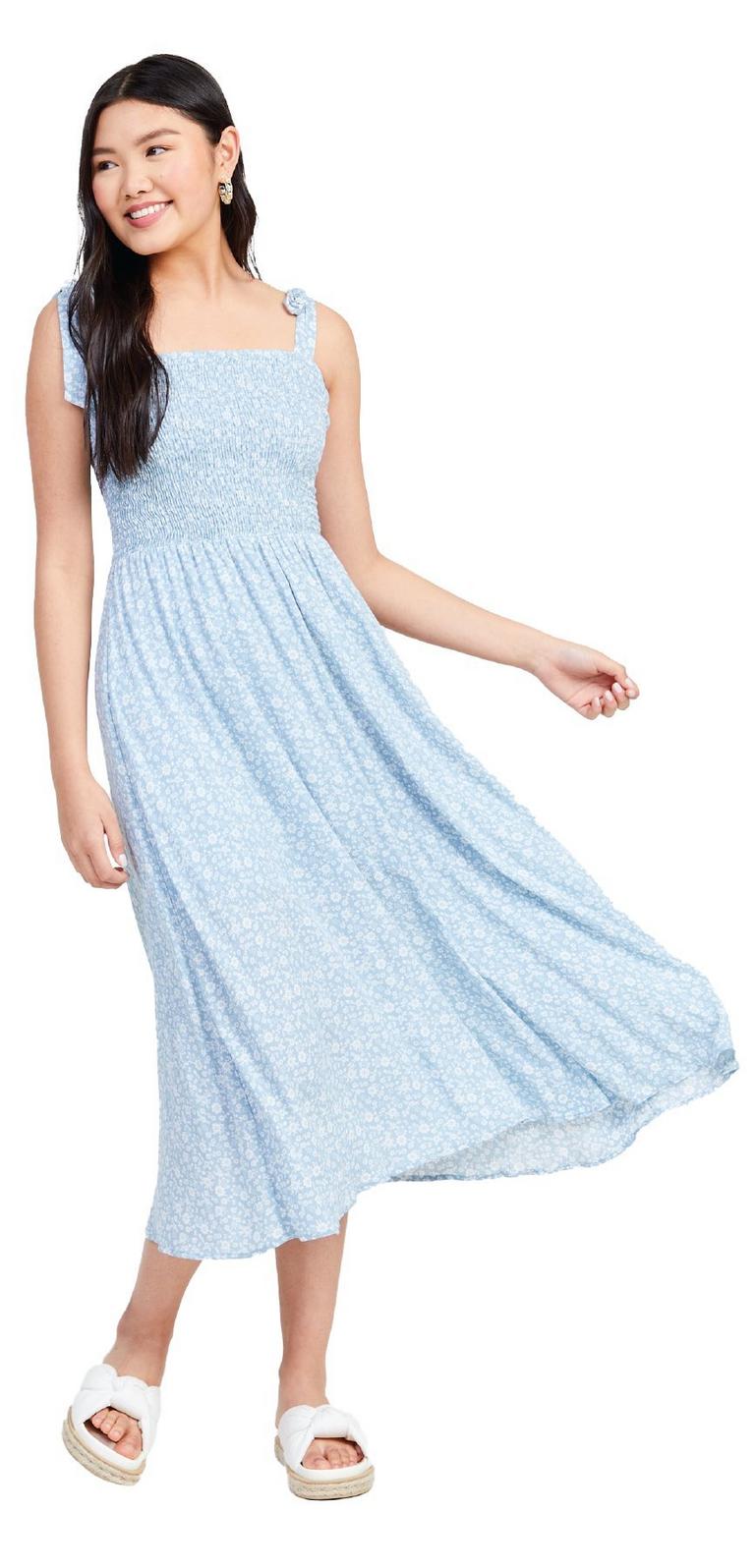 woman wearing a light blue floral sundress with white sandals