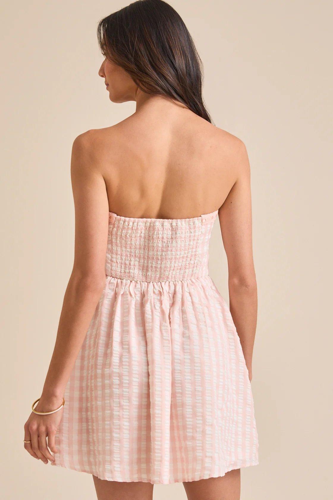 Girl wearing a light pink gingham mini dress