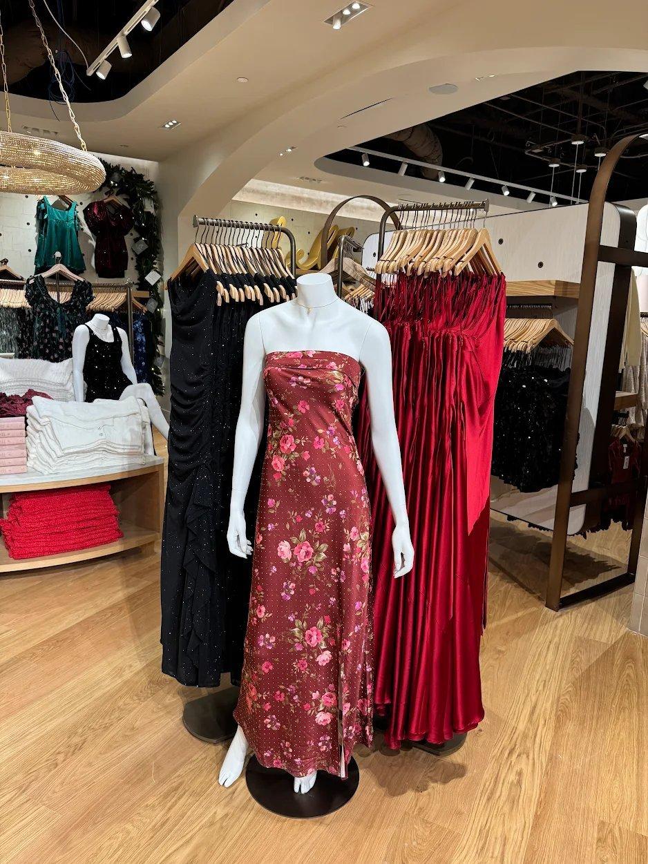 mannequin with a floral strapless dress and other hanging dresses