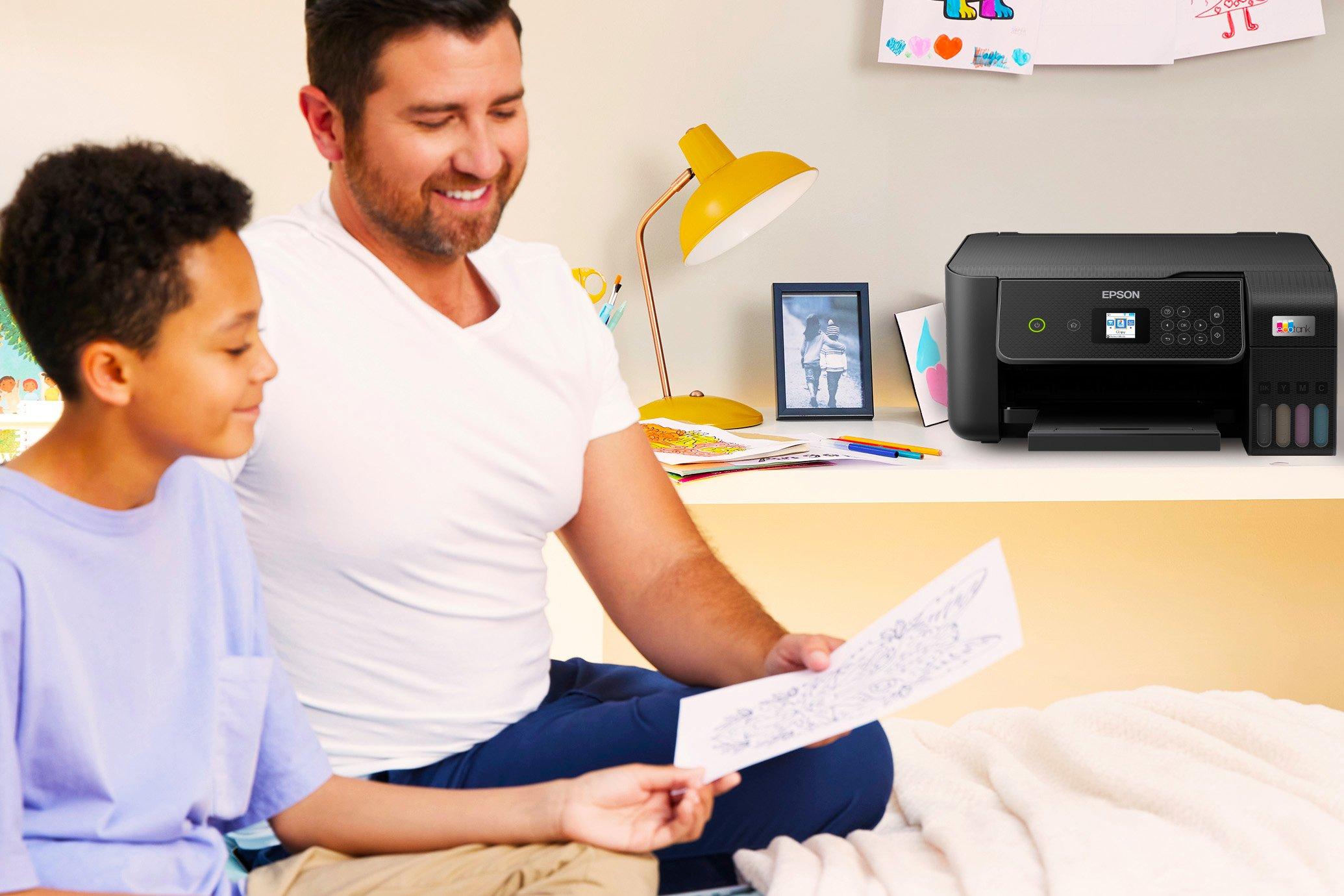 A man and a young boy looking at a printout. An Epson EcoTank is on a desk in the background.