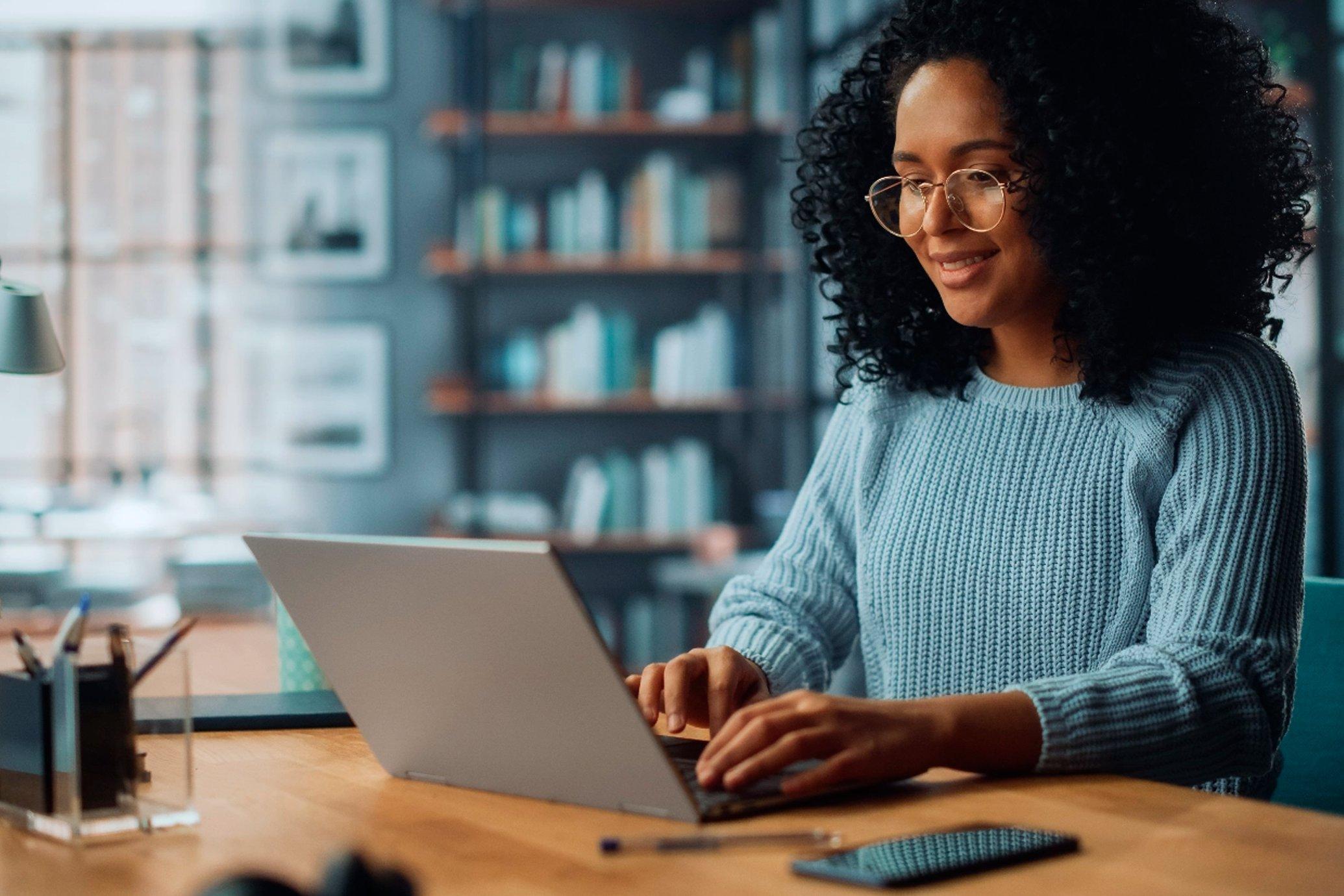 A woman smiling and using her laptop