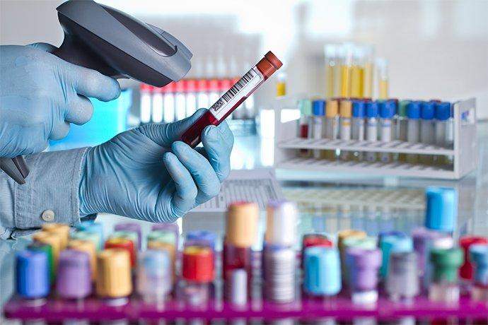 A person's hands with gloves scanning a bar code off a red vile 