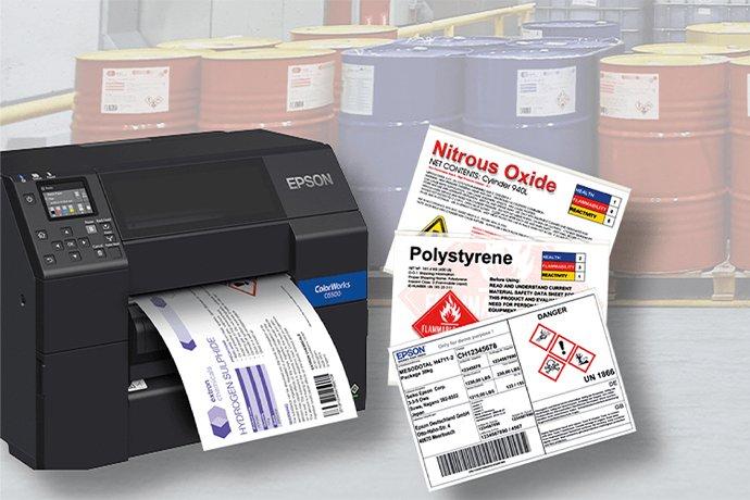An Epson ColorWorks unit with printed labels next to it, with labelled barrels on pallets in the background