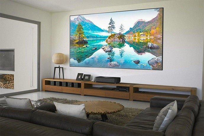 a man sitting on the floor in front of a tv with a car in the background