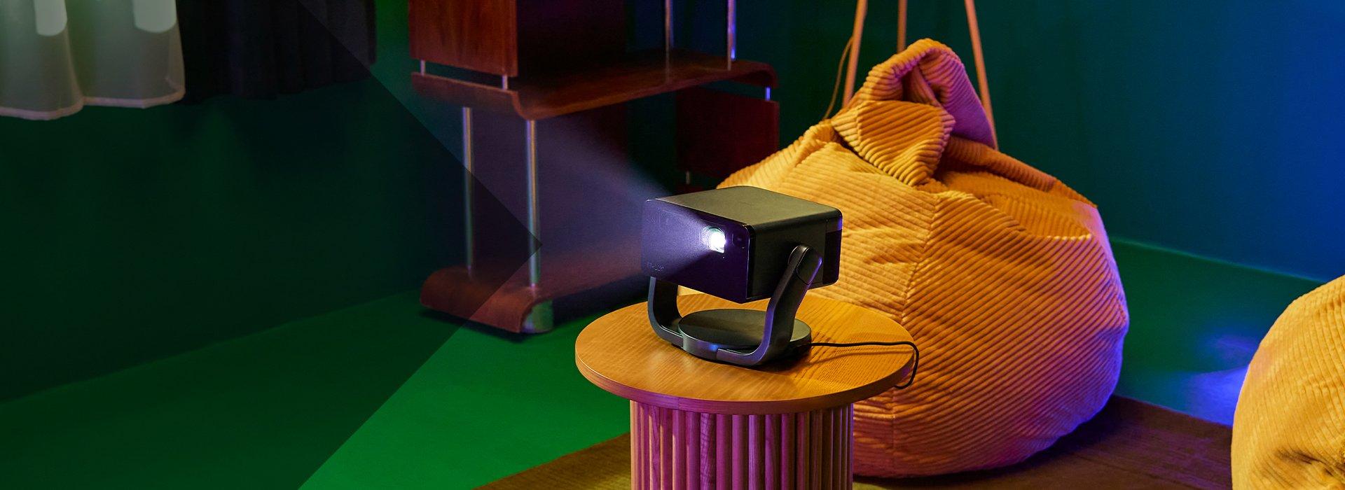 a small projector is on a stand next to a large bag