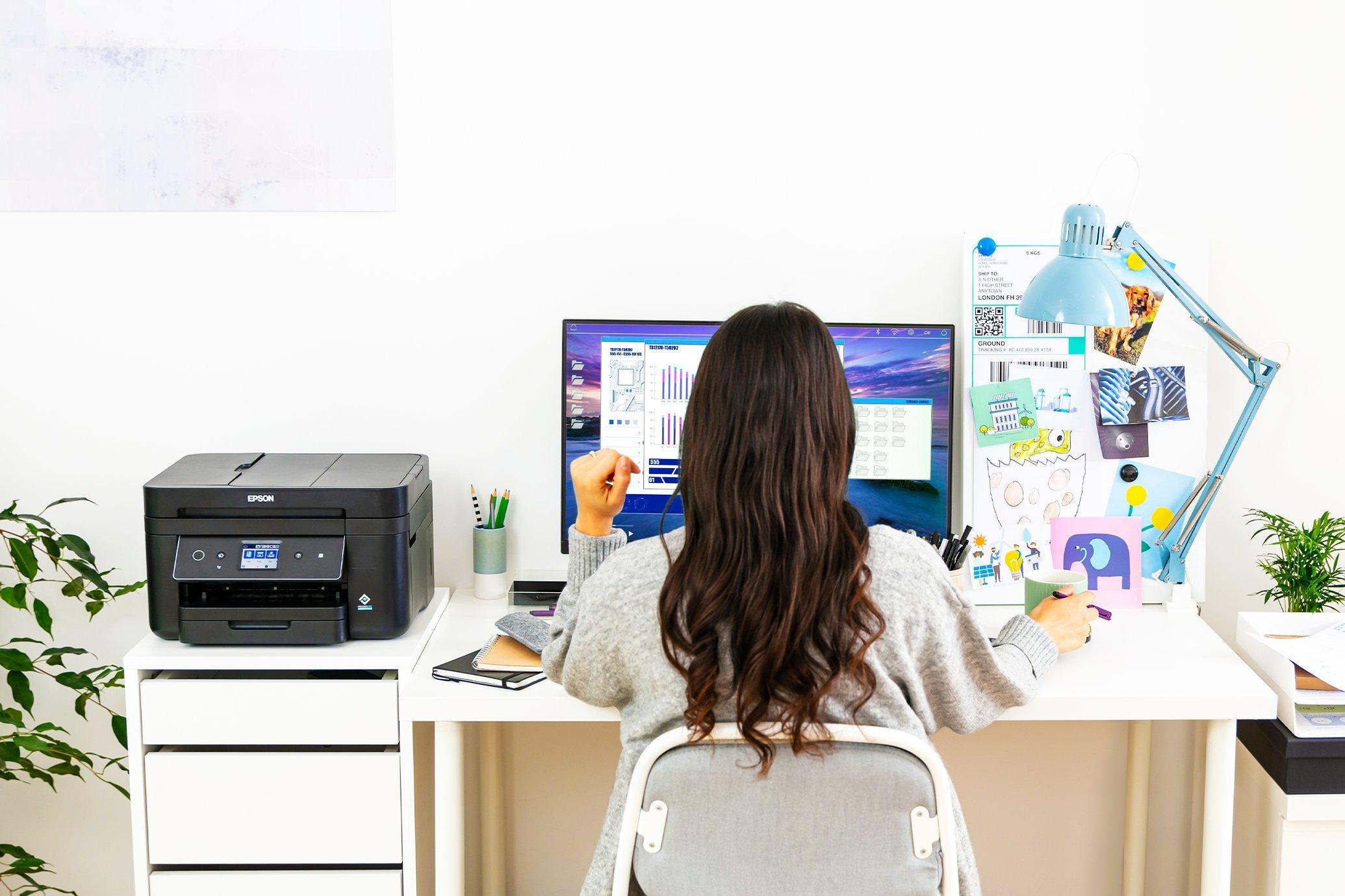 A woman at a home office desk with an Epson WorkForce printer