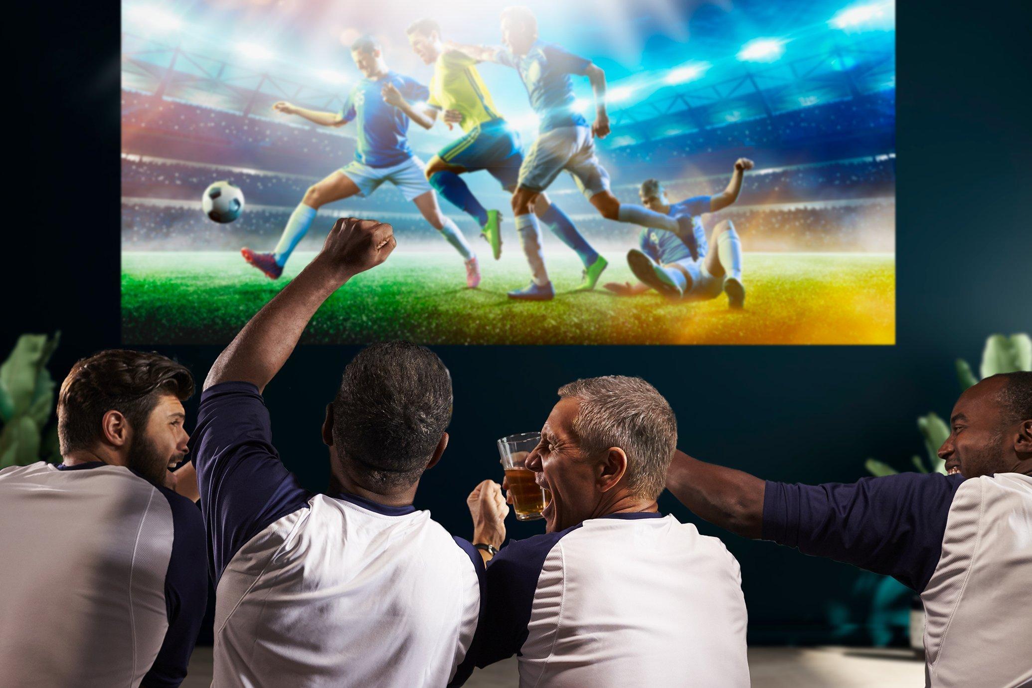 A group of friends watching a football match together on a projector screen