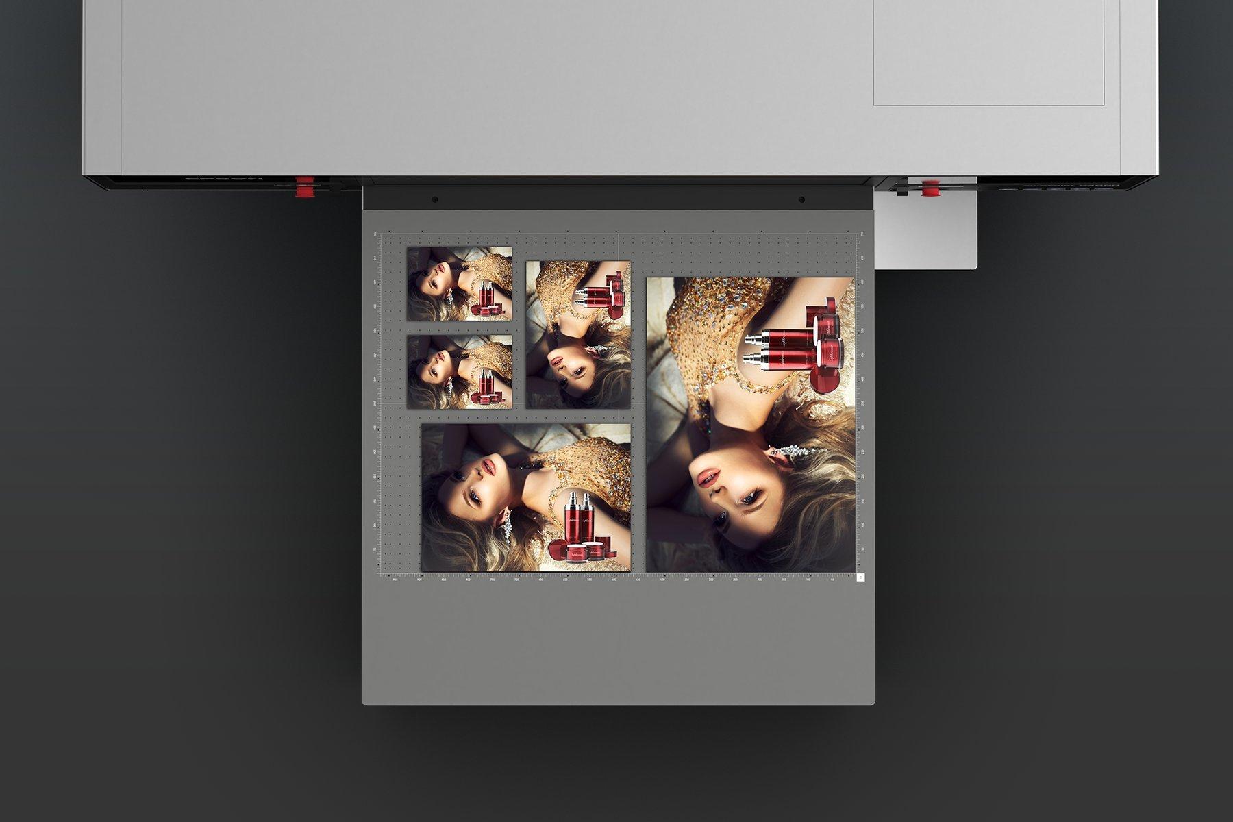 A printer outputs glossy images of a woman in a gold dress alongside nail polish and lipstick. 
