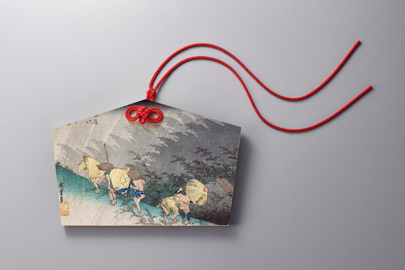A wooden ema board with a traditional Japanese painting shows travellers under rain.