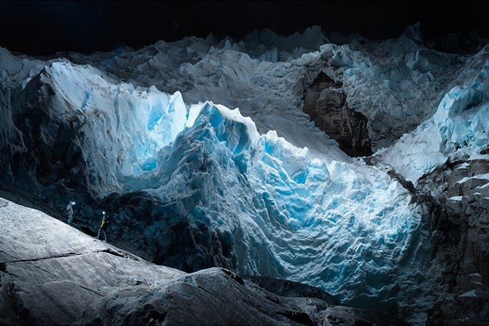 Due uomini in tenuta invernale con torce montate sulla testa in piedi contro i ghiacciai 