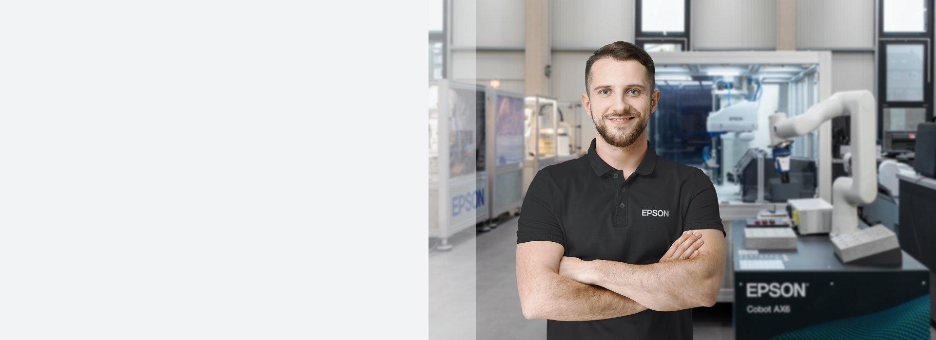 Man standing with his arms folded in front of a Cobot AX6 robot.