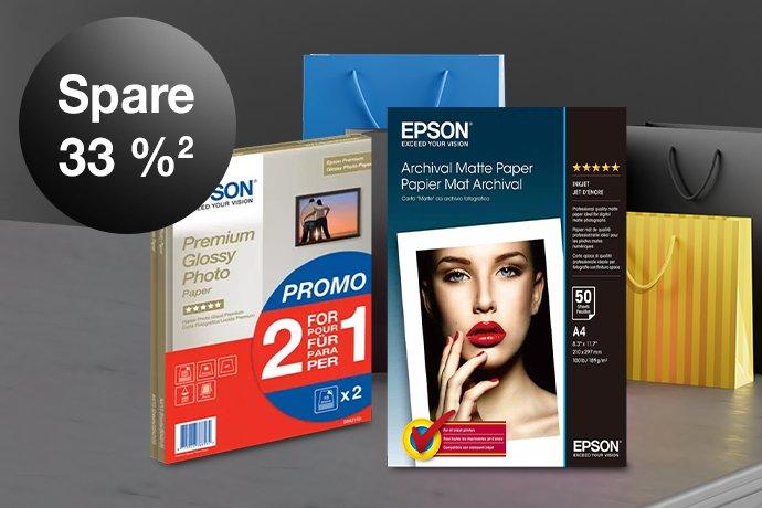 Two Epson ink cartridges against a black and grey background with colorful paper bags next to them