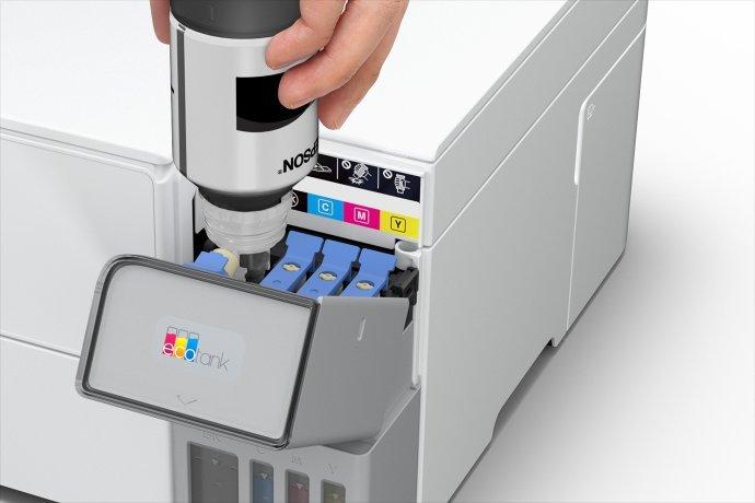 An image of a hand using a bottle of ink to fill a printer